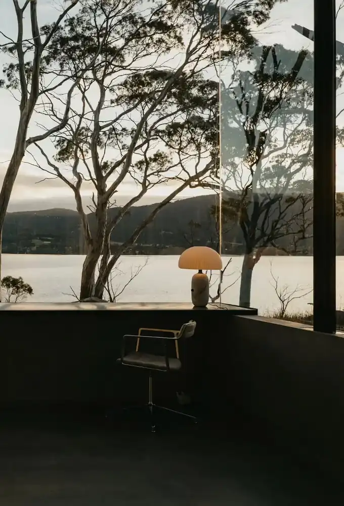 Lamp and Vipp Swivel chair at the studio desk, with gum trees and the channel at dusk