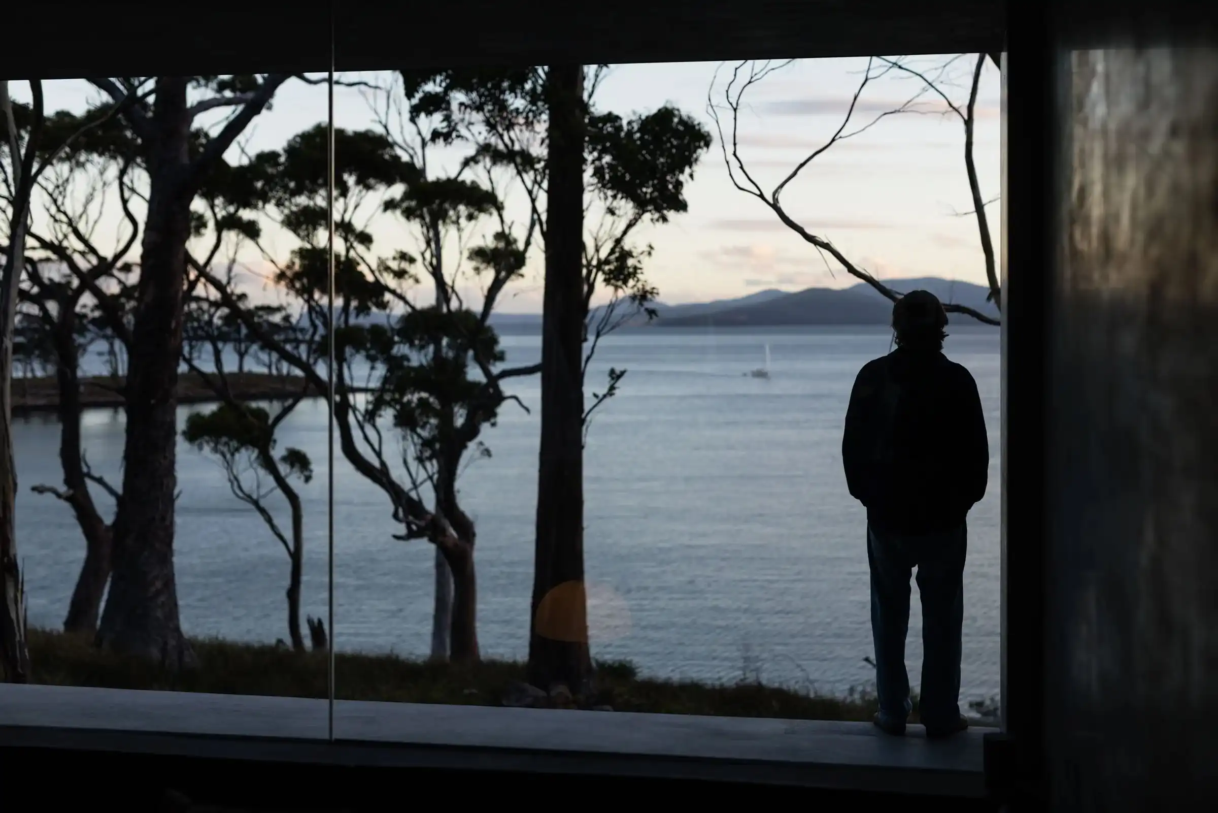 Guest at the window at dusk, with gum trees silhouetted against the channel