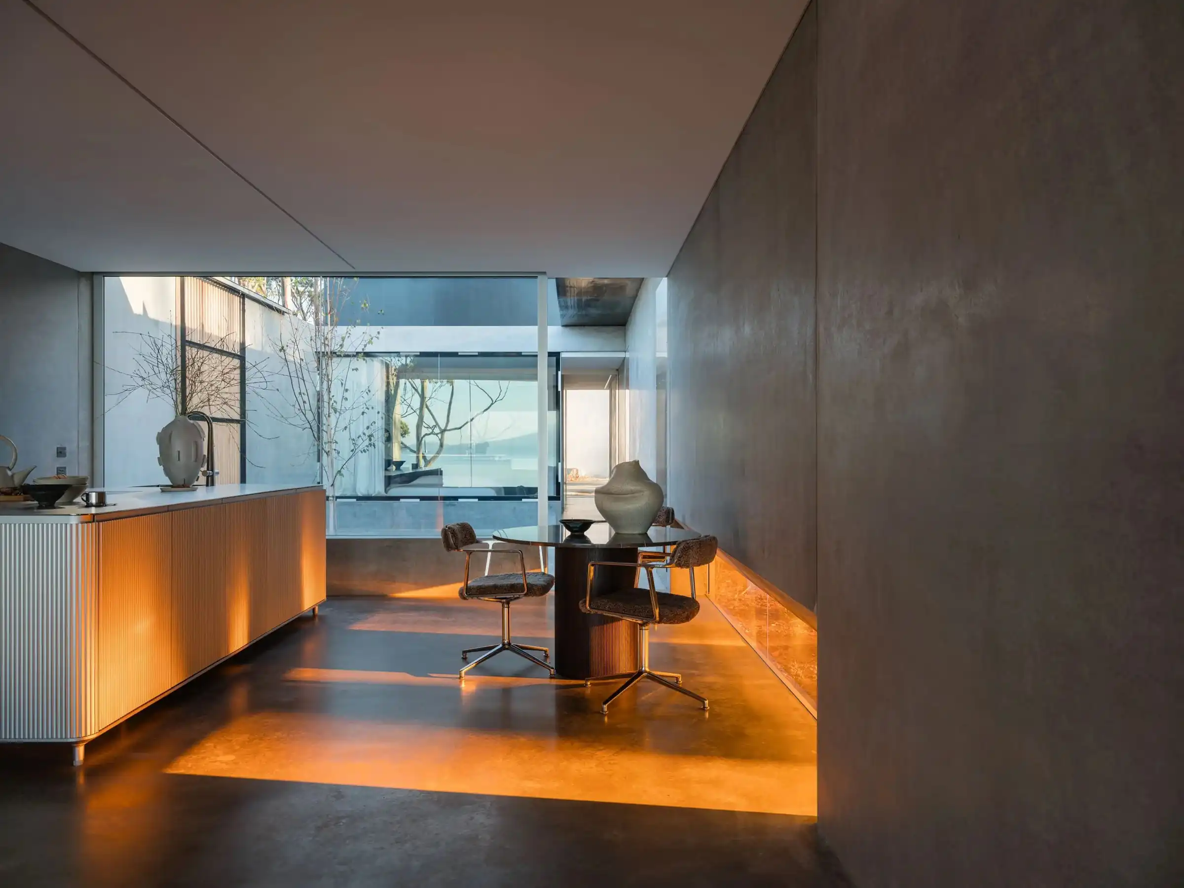 Late sun across the concrete floor beside the kitchen and dining table