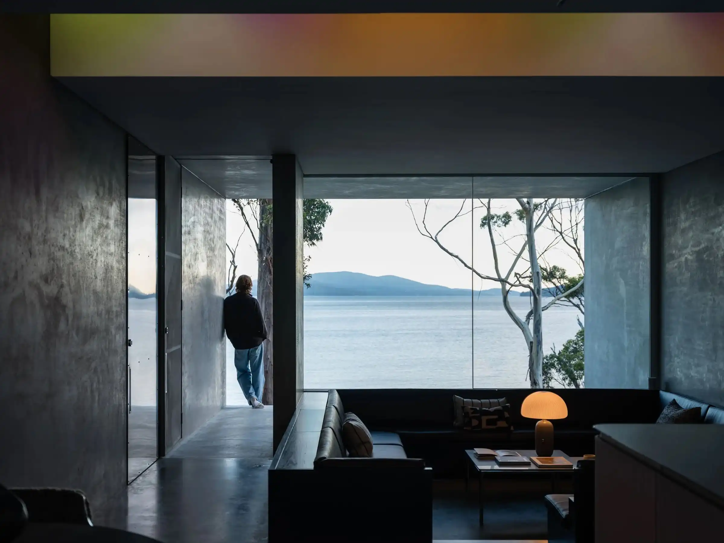 Guest at the glass wall of the living room, looking across the channel