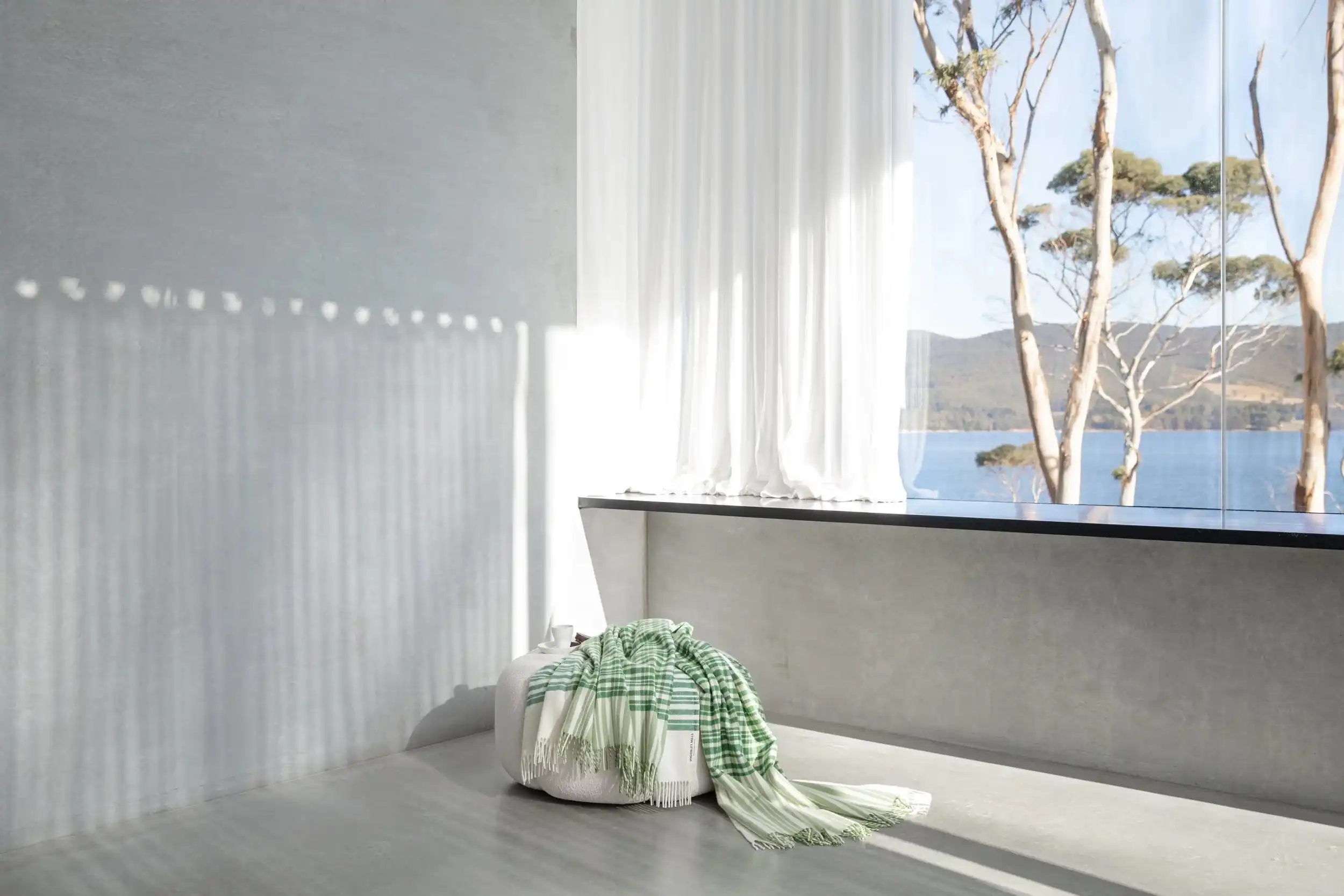 White curtain in morning light, with gum trees and the channel beyond the window