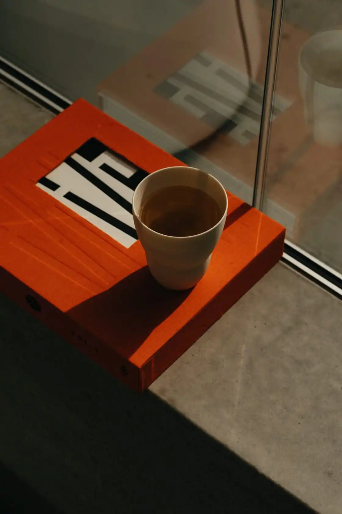 Book and a cup of tea on the window ledge in afternoon light